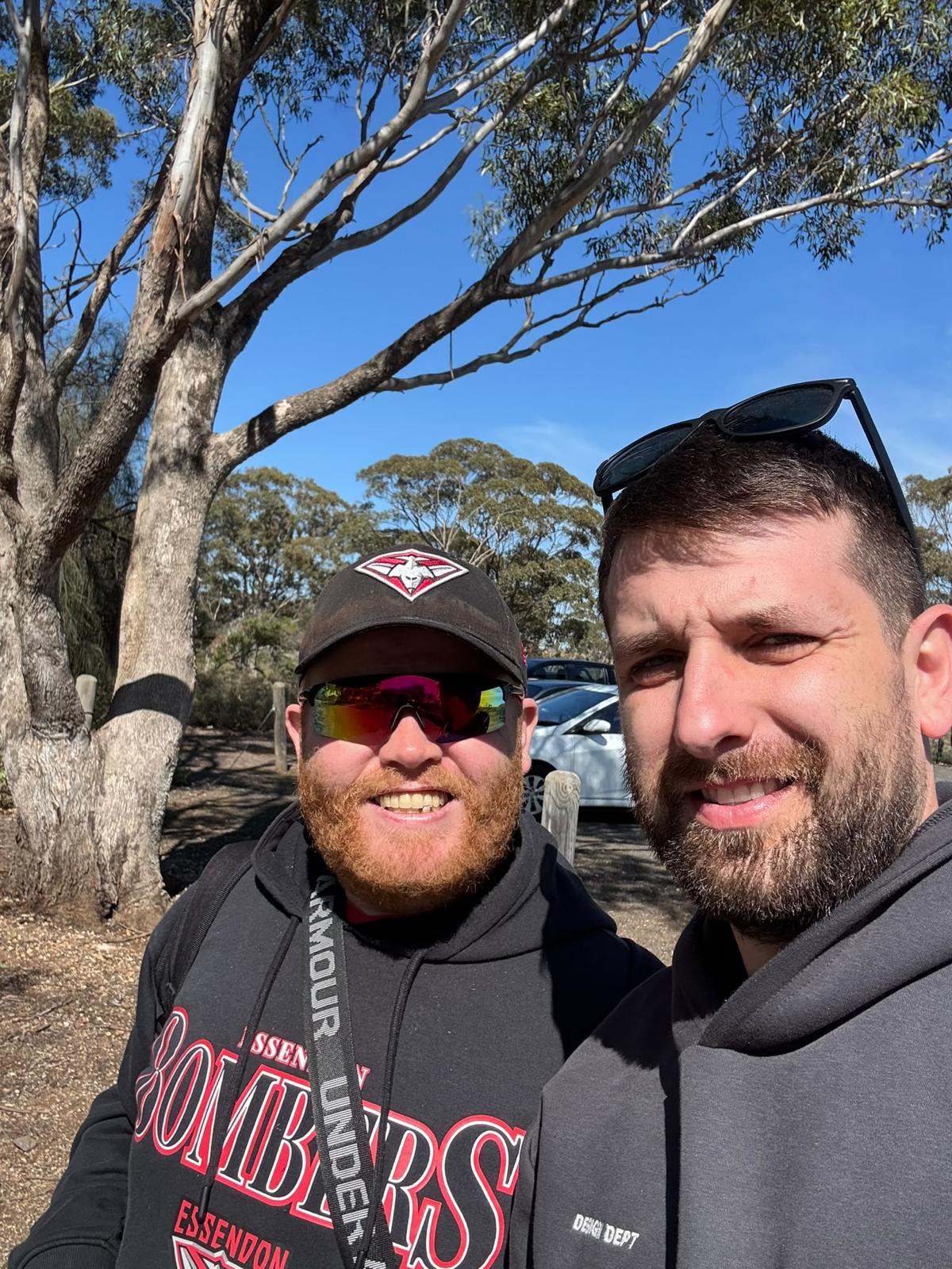 A Yours Truly support worker and a participant smiling on a walk under gum trees