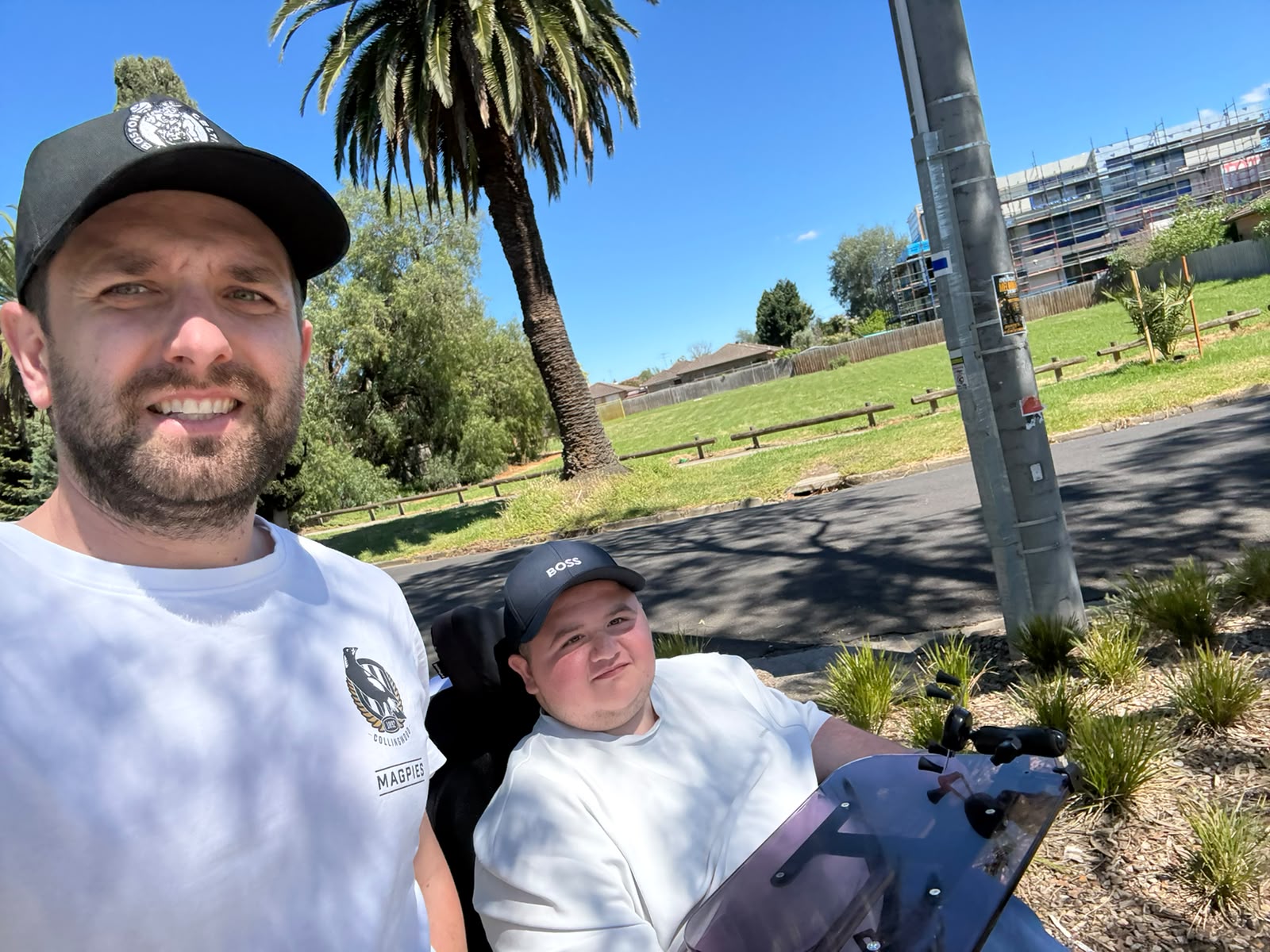 A Yours Truly support worker and a participant in a wheelchair out on a sunny day in a local park