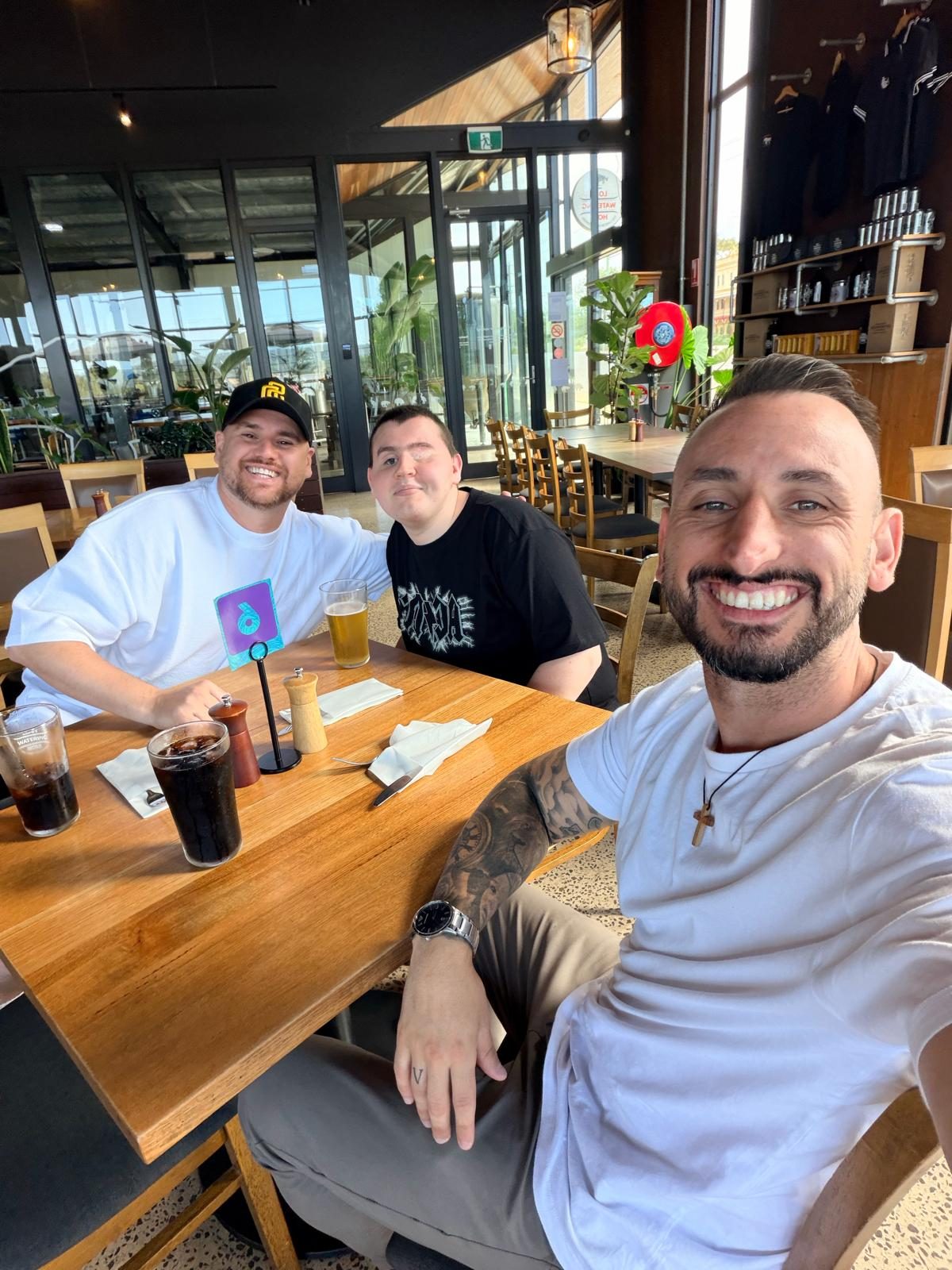 Three men smiling together at a cafe table